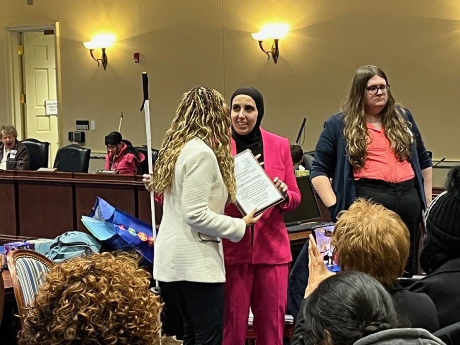 Ronza smiles speaking to Delegate who received plaque