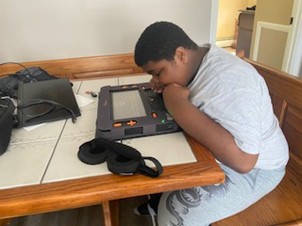 Student leans over a multi-line braille display, Monarch, touching the navigation buttons